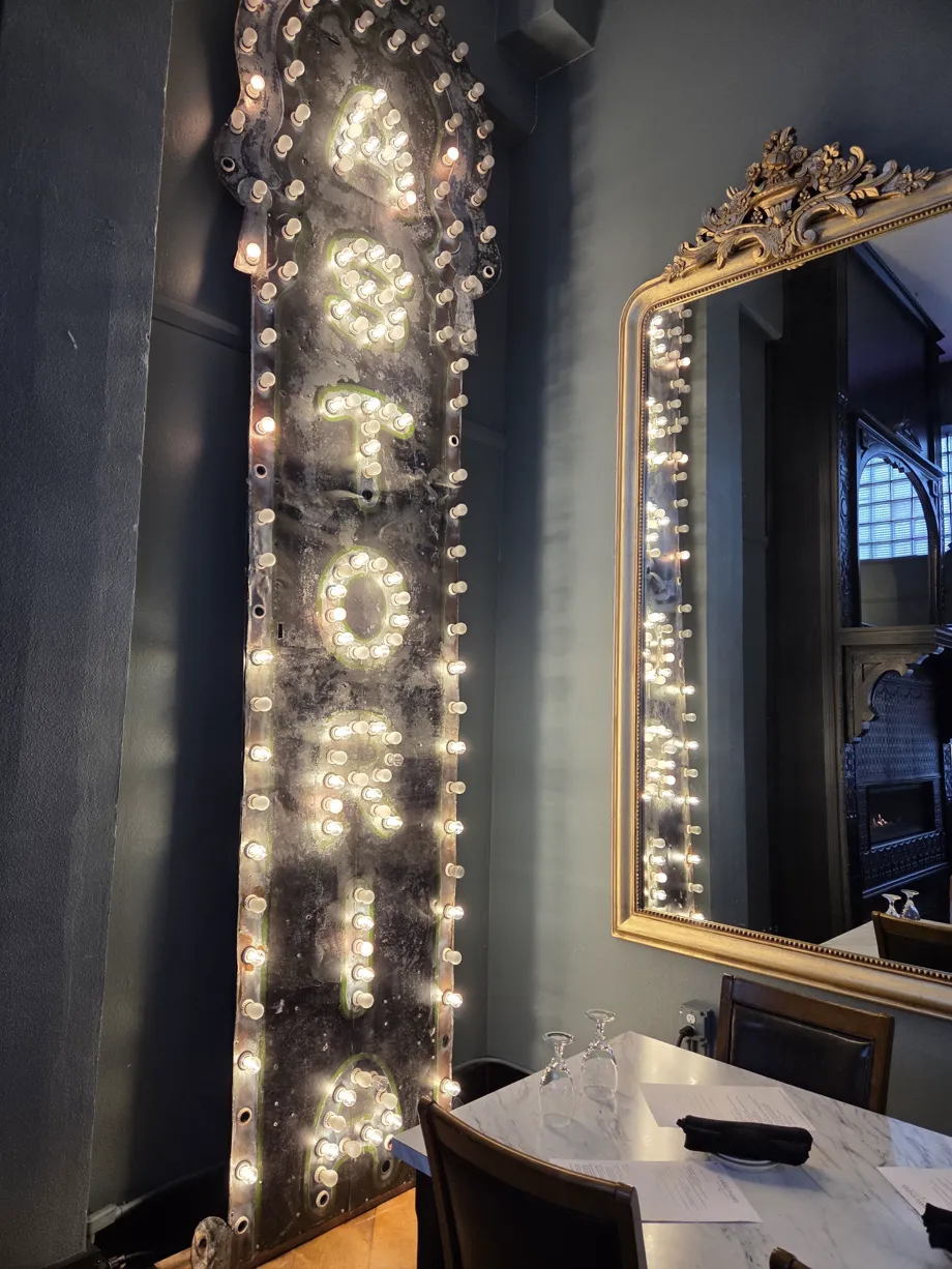 Tall ASTORIA marquee, ornate mirror, and a set table inside Carruthers